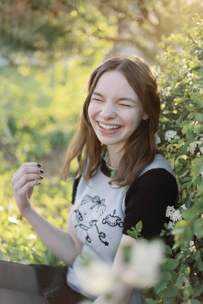 Senior girl laughing in front of blooming flowers in nature in Indianapolis