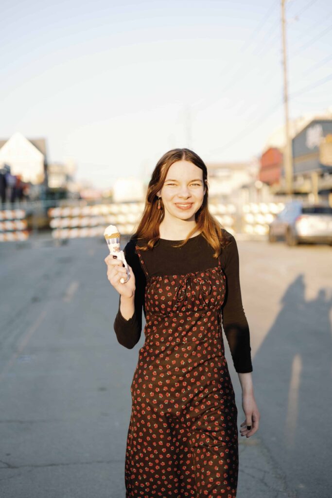 Artsy senior picture of high school senior with ice cream walking in the middle of street in Indianapolis